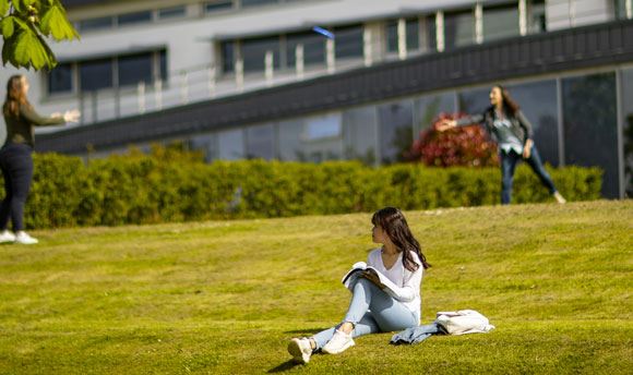Students playing frisbee on the grass outside ϲ, Edinburgh