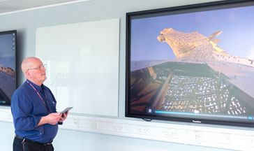 A ϲ staff member standing by 2 screens showing the Scottish Kelpies sculpture