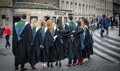 A row of ϲ graduands standing in a row wearing their gowns outside Usher Hall