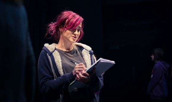A ϲ stage management student reading and making notes on a notepad on stage