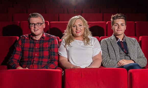 Three ϲ students sitting in plush red seats at the theatre