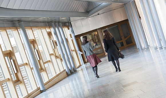 Two women walking down a corridor in ϲ hallway