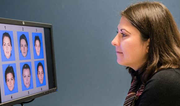 ϲ Psychology Student looking at a computer screen displaying 6 different faces numbered 1-6