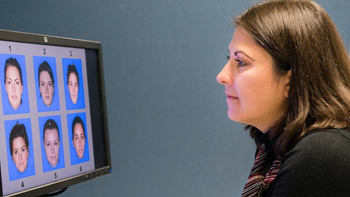 ϲ Psychology Student looking at a computer screen displaying 6 different faces numbered 1-6