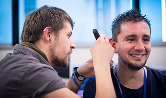 ϲ Hearing Aid Audiology student using a piece of equipment to test another student's hearing