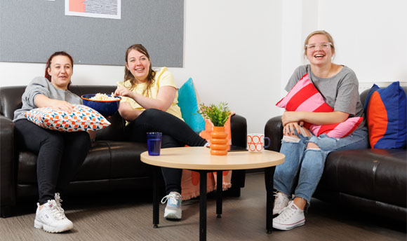 Three female students enjoy popcorn while watching a film in their ϲ Student Accommodation